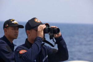 Membro da guarda costeira das Filipinas observa por binóculo durante missão de reabastecimento de tropas estacionadas em navio ancorado no Mar do Sul da China